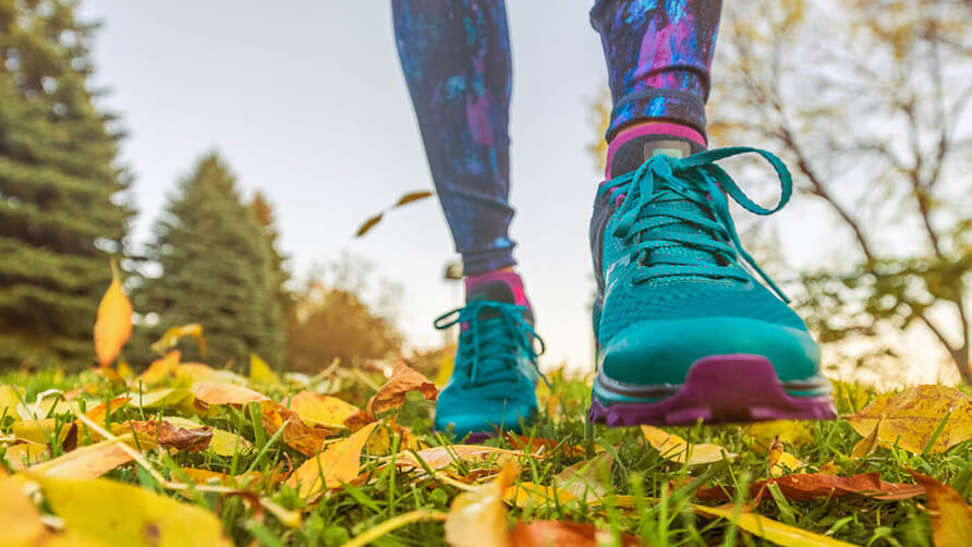 Blauw, roze hardloopschoenen op een ondergrond van herfstbladeren